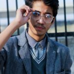 Youth in college uniform adjusting eyeglasses outdoors, Patna, India.